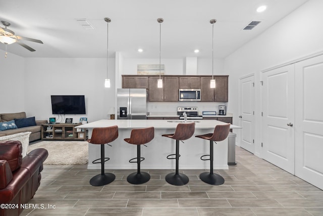 kitchen featuring visible vents, a breakfast bar area, appliances with stainless steel finishes, open floor plan, and light countertops