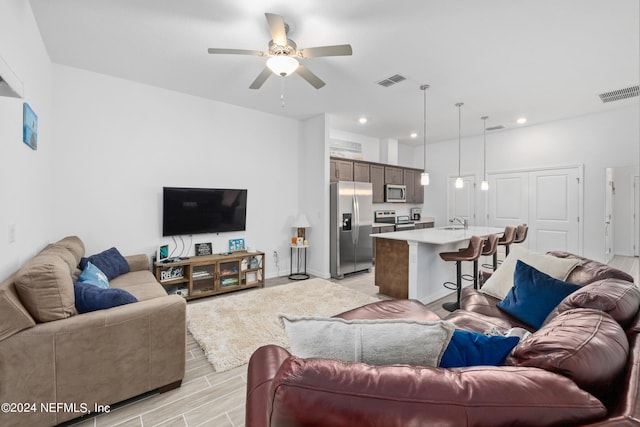 living area with a ceiling fan, recessed lighting, visible vents, and light wood finished floors