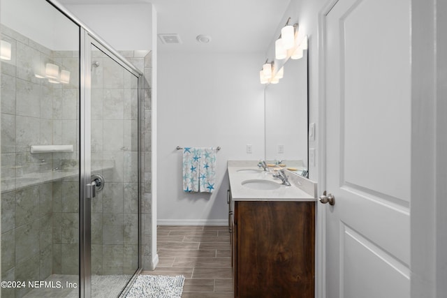 full bath with a sink, baseboards, wood tiled floor, double vanity, and a stall shower