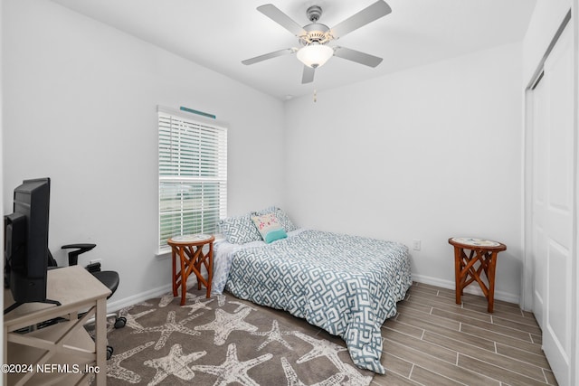 bedroom featuring baseboards, a closet, a ceiling fan, and wood tiled floor