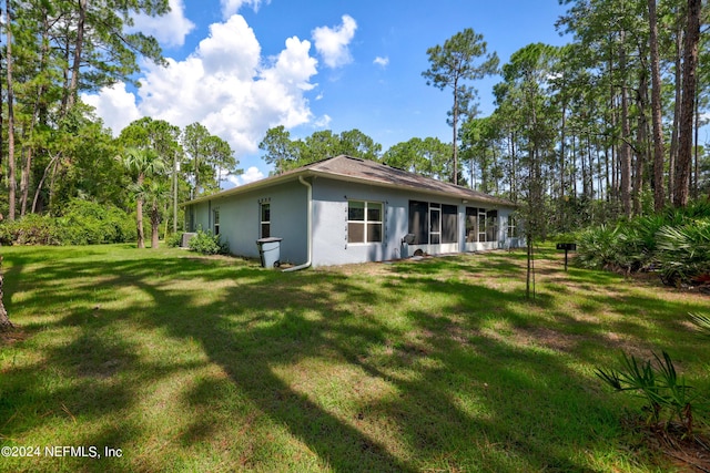 rear view of property featuring a lawn and stucco siding