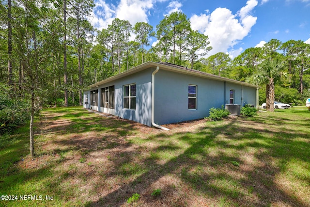 view of home's exterior with cooling unit, a yard, and stucco siding