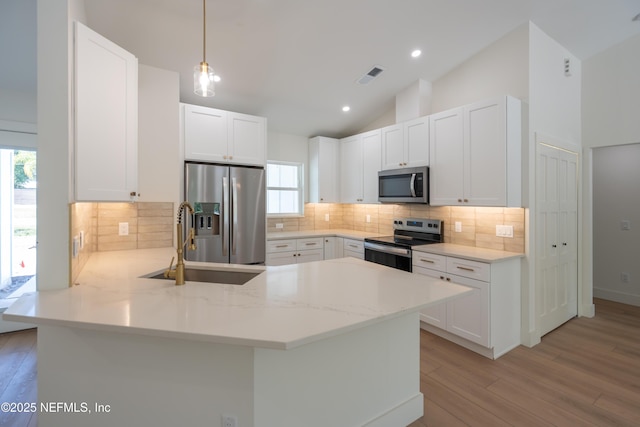 411 Royal Rd, Saint Augustine South, FL 32086 - kitchen with stainless steel appliances, a peninsula, light wood-type flooring, lofted ceiling, and decorative backsplash