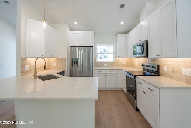411 Royal Rd, Saint Augustine South, FL 32086 - kitchen featuring appliances with stainless steel finishes, a peninsula, decorative backsplash, light stone countertops, and light wood finished floors