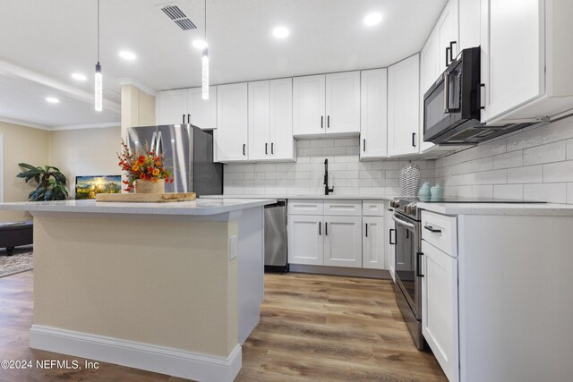 kitchen with pendant lighting, wood-type flooring, decorative backsplash, appliances with stainless steel finishes, and white cabinets