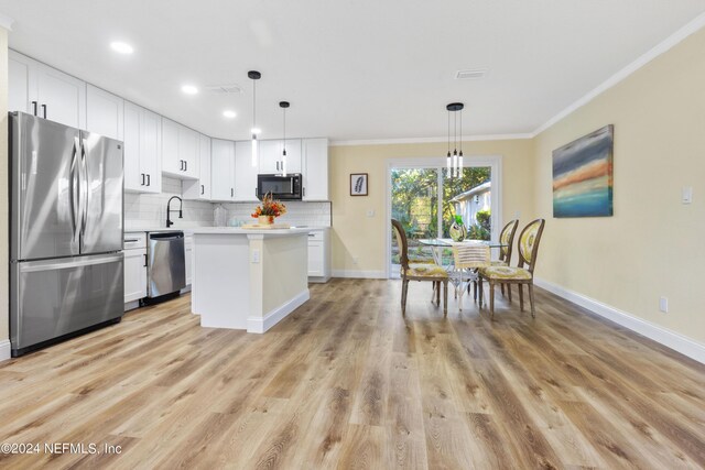 kitchen with white cabinets, appliances with stainless steel finishes, decorative backsplash, and light hardwood / wood-style floors