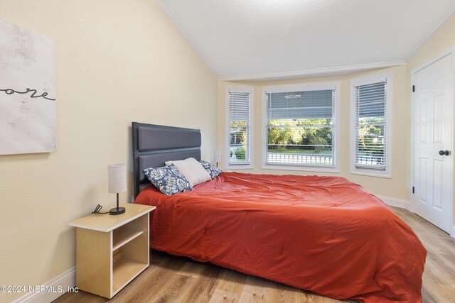 bedroom featuring light wood-type flooring and lofted ceiling