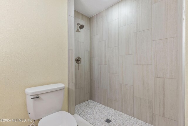 bathroom featuring toilet and a tile shower