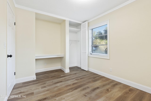 unfurnished bedroom with crown molding, a closet, and hardwood / wood-style flooring