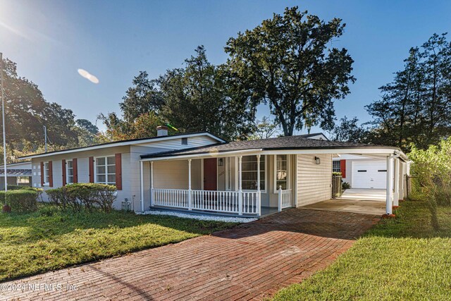 view of front of house with a garage, a porch, an outbuilding, and a front yard