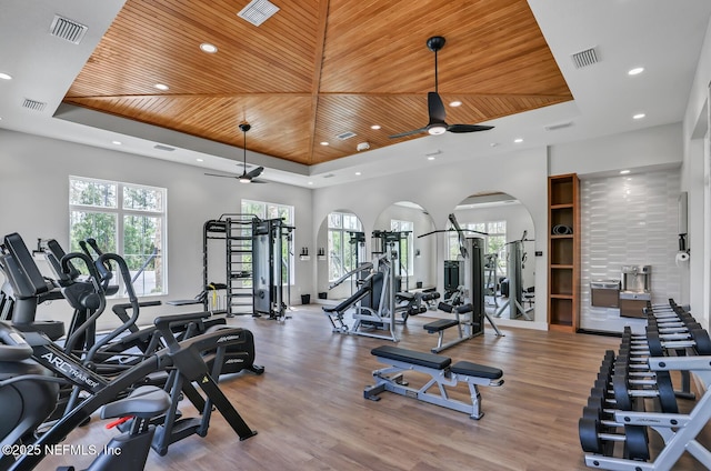 gym with wood ceiling, ceiling fan, a tray ceiling, and a wealth of natural light