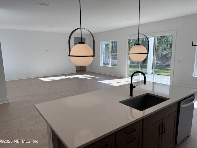 kitchen featuring pendant lighting, sink, dishwasher, a wealth of natural light, and a center island with sink