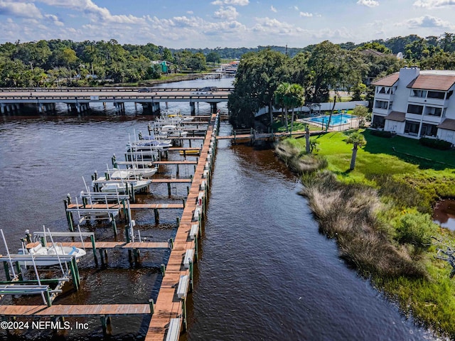 view of dock with a lawn and a water view