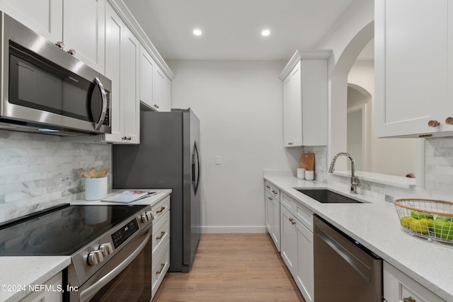 kitchen featuring light hardwood / wood-style floors, light stone countertops, sink, and stainless steel appliances