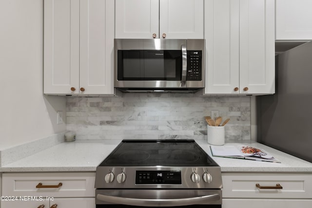 kitchen featuring light stone countertops, stainless steel appliances, white cabinets, and decorative backsplash