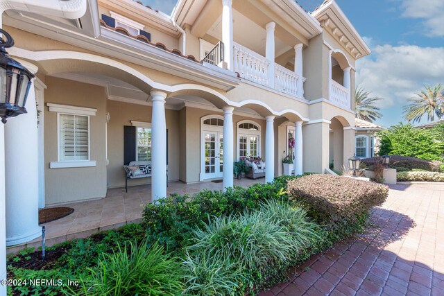 view of front of home with a patio, a balcony, and french doors