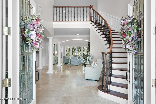 foyer with a high ceiling, decorative columns, and ornamental molding