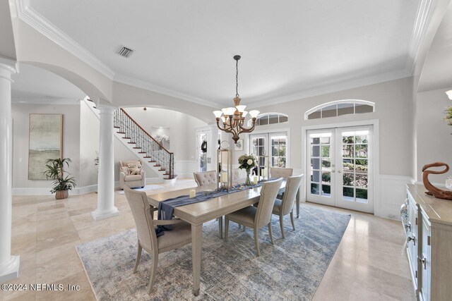 dining room featuring crown molding, a notable chandelier, french doors, and ornate columns