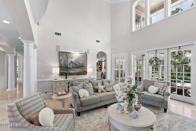 living room featuring ornate columns, plenty of natural light, ornamental molding, and french doors