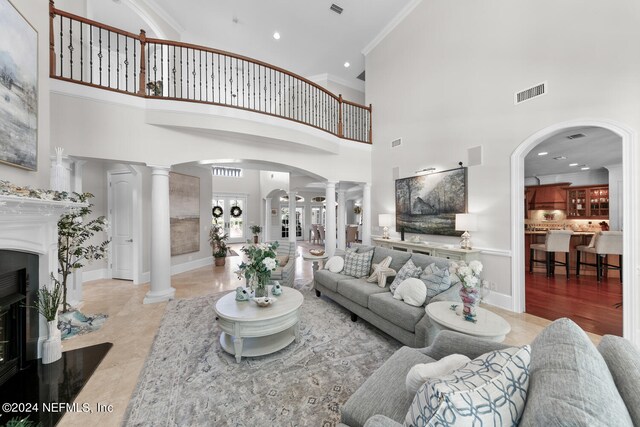 living room featuring crown molding, a high ceiling, and decorative columns