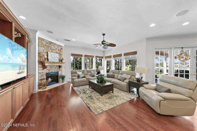 living room featuring a fireplace, dark wood-type flooring, ornamental molding, and ceiling fan