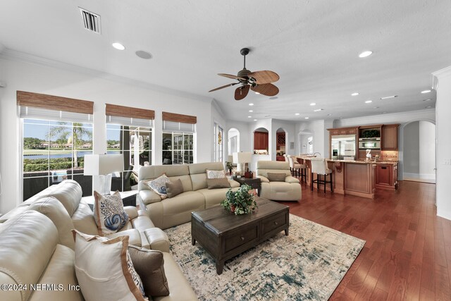 living room featuring ceiling fan, dark hardwood / wood-style floors, and ornamental molding