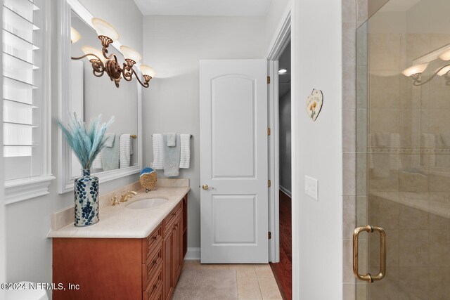 bathroom with tile patterned flooring, a shower with door, and vanity