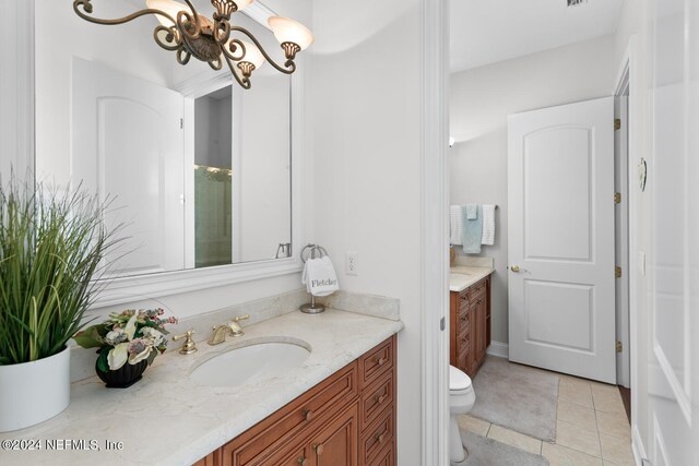 bathroom featuring tile patterned floors, toilet, a notable chandelier, a shower, and vanity