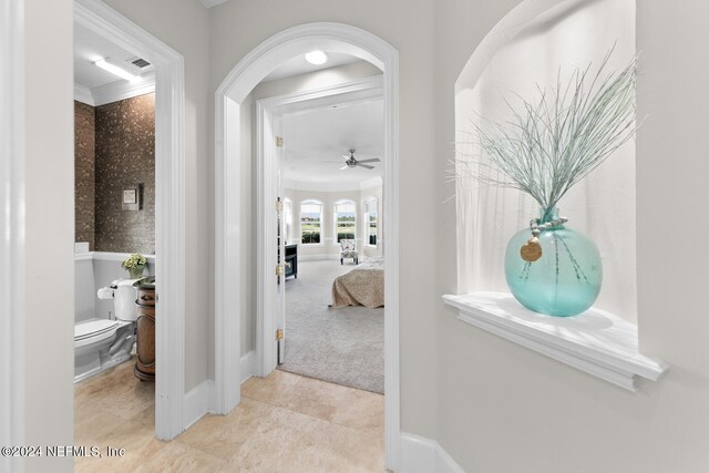 corridor with crown molding and light colored carpet