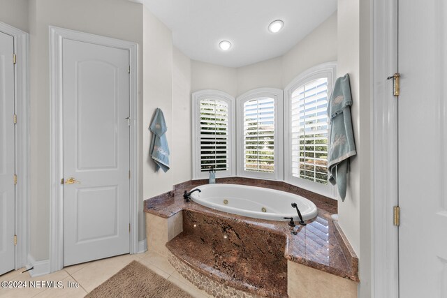 bathroom featuring a relaxing tiled tub and tile patterned flooring