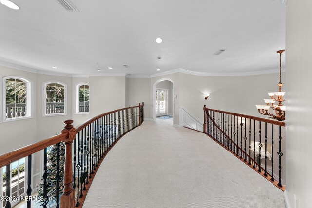 hall with plenty of natural light, carpet flooring, a notable chandelier, and crown molding