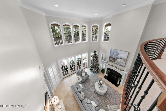 living room with plenty of natural light, a high ceiling, ornamental molding, and a fireplace