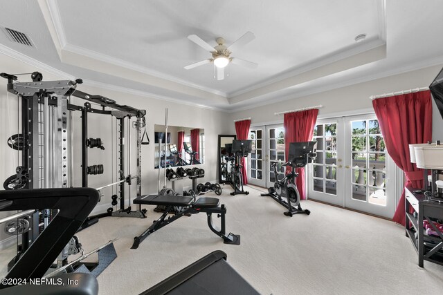 exercise room featuring a raised ceiling, ceiling fan, light colored carpet, and french doors