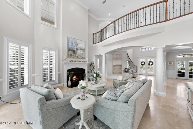 living room with decorative columns, a wealth of natural light, crown molding, and french doors