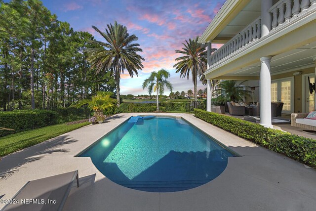 pool at dusk featuring outdoor lounge area and a patio