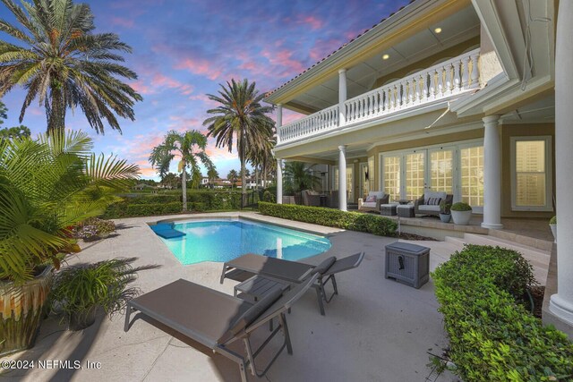 pool at dusk with a patio area and outdoor lounge area