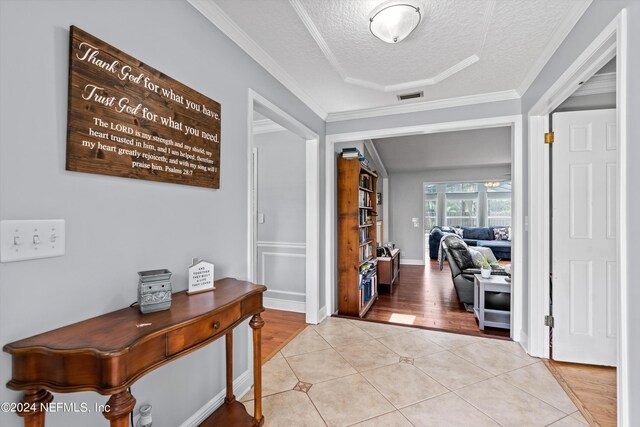 hall featuring a textured ceiling, ornamental molding, and light wood-type flooring