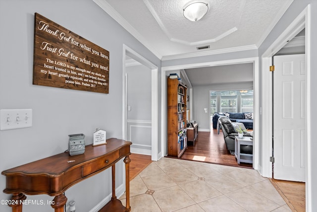 entryway featuring light tile patterned floors, crown molding, visible vents, and a textured ceiling