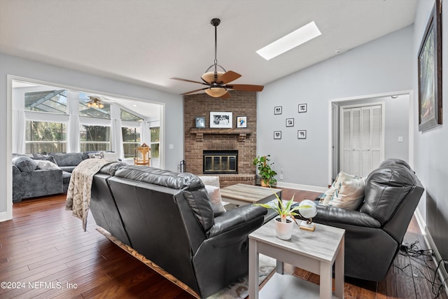 living area featuring lofted ceiling with skylight, a fireplace, wood finished floors, and a ceiling fan