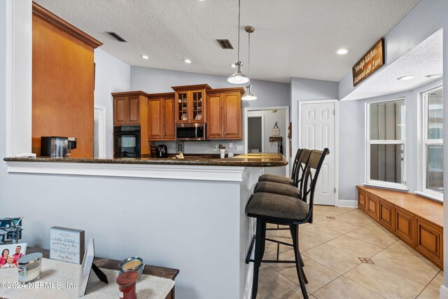 kitchen with light tile patterned flooring, oven, dark stone counters, and vaulted ceiling