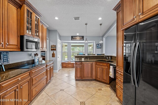 kitchen featuring light tile patterned floors, decorative light fixtures, sink, black appliances, and a textured ceiling