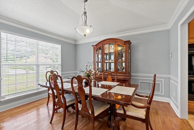 dining space featuring light wood finished floors, a textured ceiling, visible vents, and crown molding