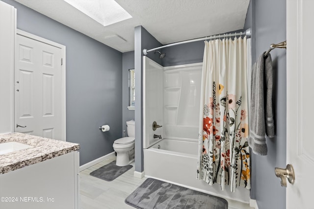 full bathroom featuring a textured ceiling, toilet, a skylight, vanity, and shower / bath combo with shower curtain