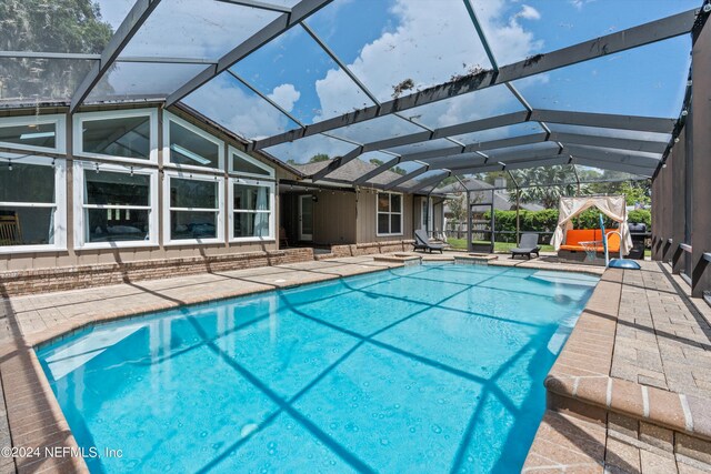 view of pool with glass enclosure and a patio