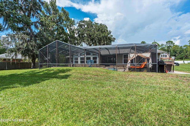 back of house with a yard and a lanai