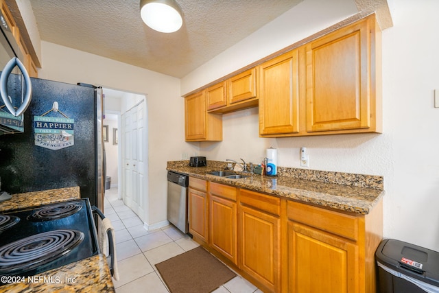 kitchen featuring dark stone countertops, light tile patterned floors, stainless steel appliances, sink, and a textured ceiling