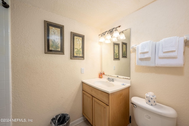 bathroom with a textured ceiling, vanity, and toilet