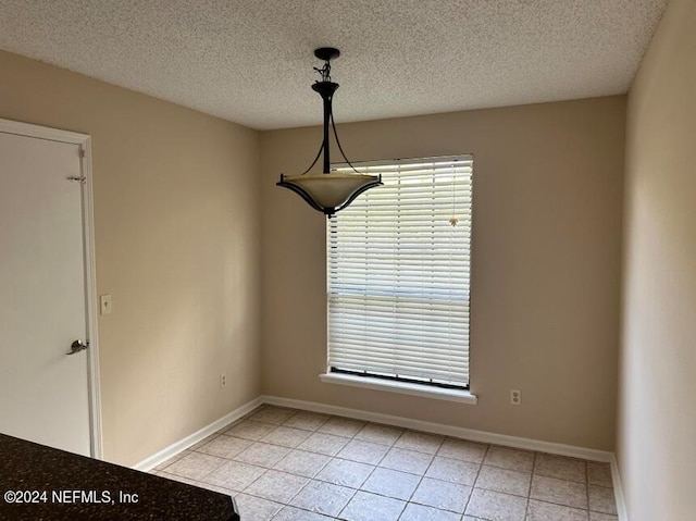 unfurnished dining area with a textured ceiling and light tile patterned flooring