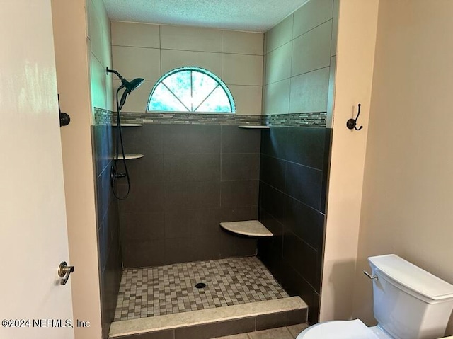 bathroom with tiled shower, toilet, and tile patterned floors