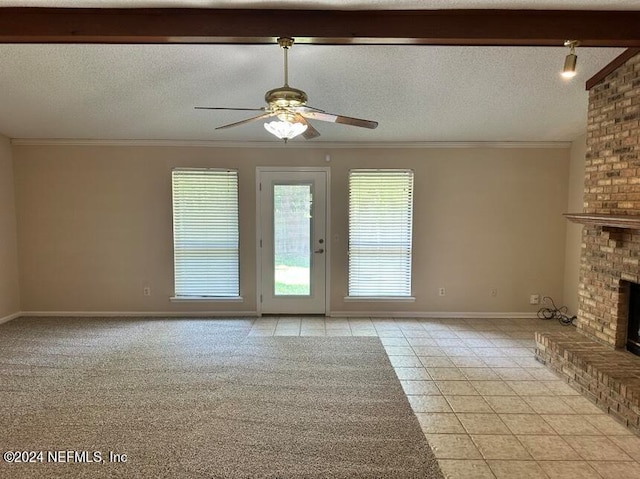 unfurnished living room featuring a fireplace, a textured ceiling, light tile patterned floors, ceiling fan, and brick wall